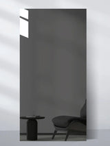 Gray glossy wood veneer wall panel sample reflecting a lounge chair and round side table