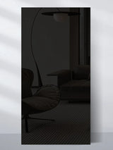 Dark glossy wood veneer wall panel sample reflecting a modern lounge chair, sofa, and floor lamp