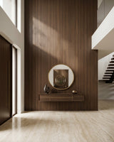 Walnut wood veneer panel installed as a tall entryway accent wall behind a round mirror and console