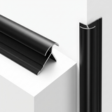 Black aluminum alloy round outside corner trim shown loose and fitted vertically on a white corner