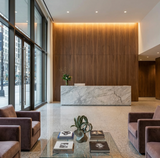 Commercial lobby with ash wood veneer panels behind a marble reception desk