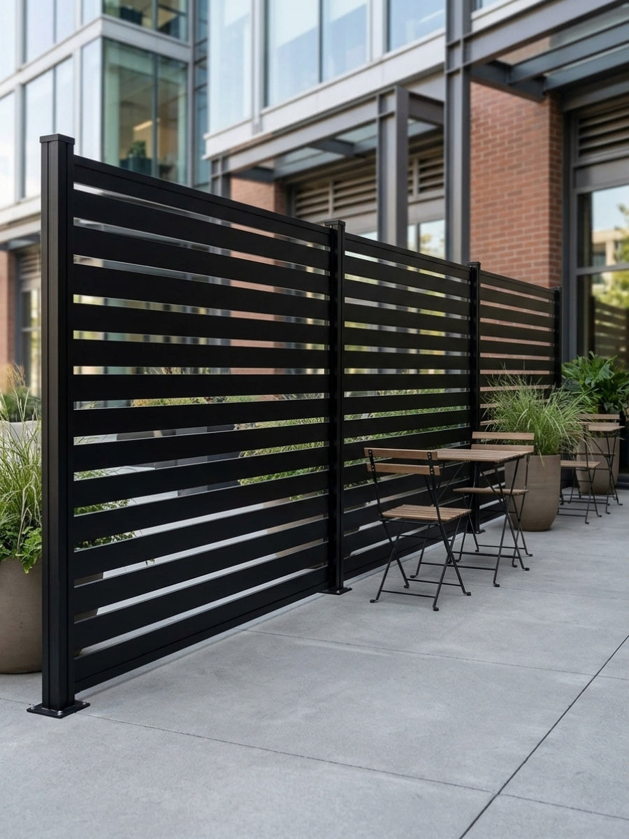 Dark aluminum open slat fence panels installed as a privacy divider around an urban patio seating area