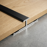 Black aluminum alloy H trim joining two wood-look panels on a gray surface