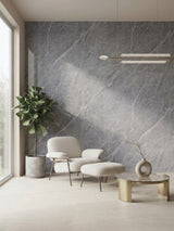 Ash gray marble-look PVC feature wall behind a cream lounge chair, ottoman, plant, and round table